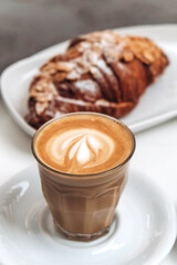 A cup of delicious coffee with a puff croissant in a cozy cafe setting
