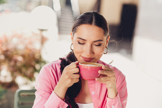 Elegant woman enjoying a cup of coffee in the city outdoors on a sunny day, showcasing casual and stylish lifestyle activities