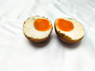 A photo of grilled salted egg on white background. Grilled salted egg is cut in half. Food culinary from indonesia, black color smoked salted egg.
