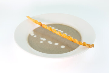 Smooth creamy mushroom soup paired with bread sticks on white background