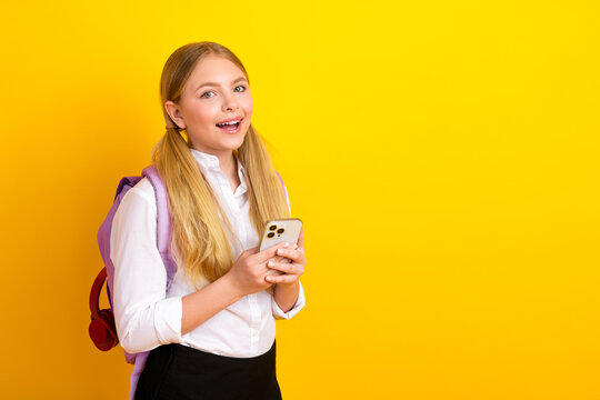 Cheerful student using smartphone against yellow background, promoting education and back to school concepts