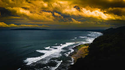 Fototapeta premium A moody coastal landscape featuring powerful waves crashing against the shore under a dramatic and stormy sky.