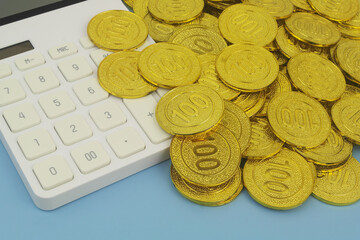 Close up of calculator and many gold coins