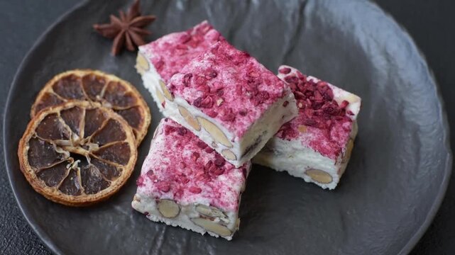 Nougat or white caramel with hazelnuts and pistachios and strawberry pieces. White nougat with nuts, sweets for the festive table