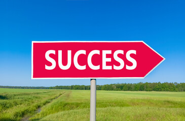 Success symbol. Concept word Success on beautiful red road sign. Beautiful blue sky green grass and forest peaceful nature background. Business success concept. Copy space.