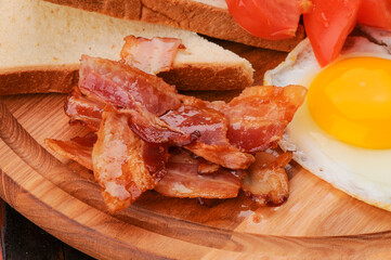 breakfast egg with bacon on a wooden board macro photo
