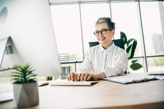 Confident mature businesswoman working in modern office using desktop computer with a professional and engaging demeanor
