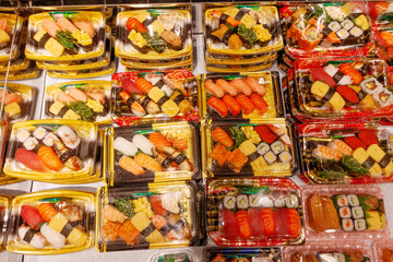 Colorful assortment of sushi and sashimi displayed in plastic containers for culinary enjoyment