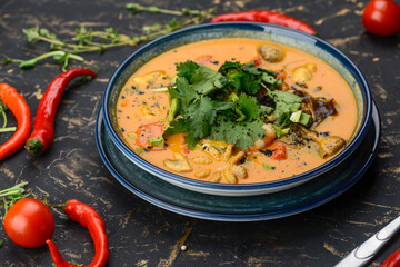 Tom yam soup with octopus pepper in a blue plate on a background