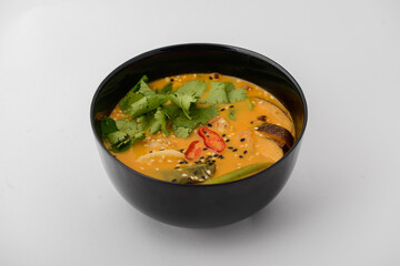 Tom yam soup in a black plate on a white background