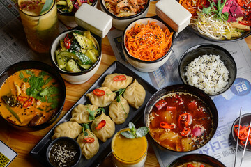 the table is set with a large number of Korean dishes in dark-colored dishes
