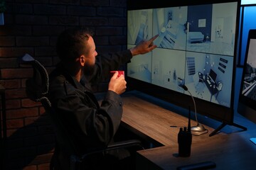 Security guard monitoring CCTV cameras in office at night