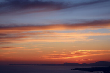 Obraz premium Colorful coastal sunset over calm sea with dramatic clouds