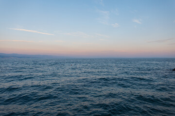 Minimalist photo of sea horizon and soft pastel sunset sky. Ideal for travel, mindfulness, and coastal lifestyle visuals. Scenic view of calm sea water and clear sky. Relaxing background for wellness,