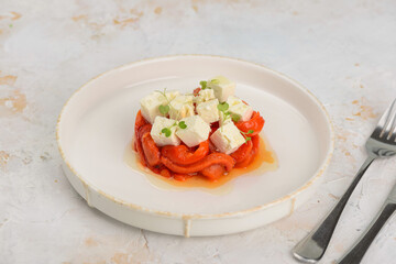 appetizer salad with paprika and cheese in a plate macro on a light background
