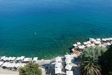 Beautiful seaside landscape of Opatija, Croatia, showing turquoise water, relaxing beach area with umbrellas, and people swimming in the Adriatic Sea