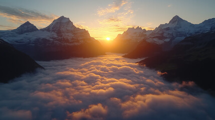 Spectacular golden light from a rising sun illuminates a vast cloud inversion filling a beautiful mountain valley below snowy peaks.