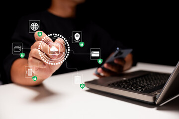 A person interacts with digital icons representing technology and connectivity, focusing on a laptop and smartphone against a dark background.