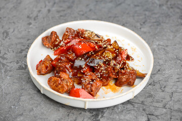 pulled pork with eggplant and tomatoes on a white plate