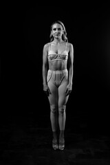 Confident fitness model posing in pink sportswear on black background