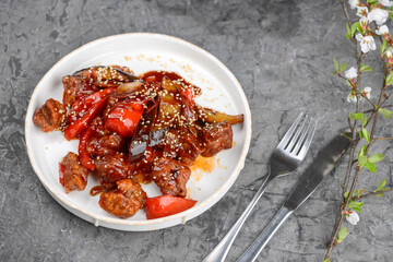 pulled pork with eggplant and tomatoes in a white plate on a gray background with decor