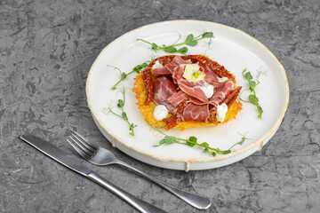 omelet with ham and herbs in a white plate on a gray background