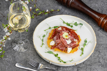 omelet with ham and herbs in a white plate on a gray concrete background with wine