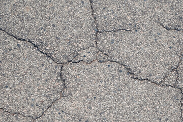 A cracked and broken pavement with a lot of rocks on it