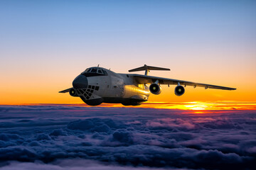 White wide body transport freight aircraft fly above the cumulus sunrise sky