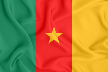 flag of the Republic of Cameroon with three stripes and a star on satin fabric with folds and shadows