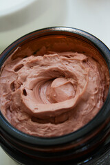 close up of a chocolate mousse Pink clay face mask or chocolate mousse in glass jar closeup view 
