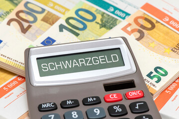 Im Display von einem Taschenrechner steht das Wort Schwarzgeld über vielen Euro Banknoten -...
