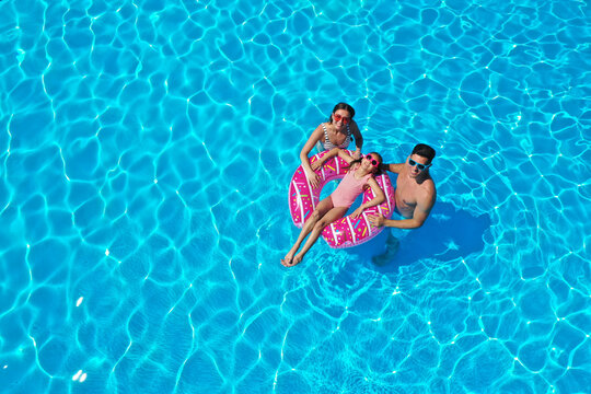 Happy family with inflatable ring in swimming pool. Summer vacation
