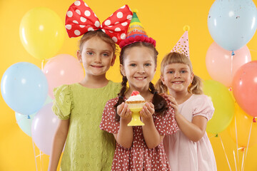 Birthday celebration. Kids with cupcake and balloons on orange background