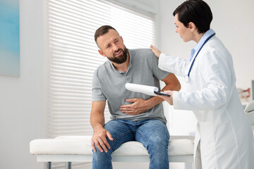 Gastroenterologist consulting patient with stomach pain in clinic