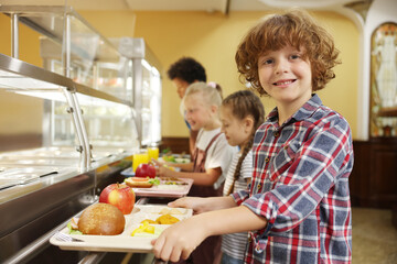 Little boy with tray of tasty food in school canteen, selective focus © New Africa