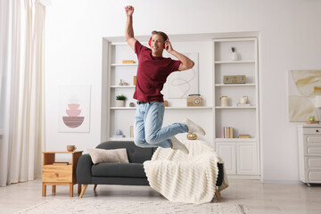 Happy man jumping while listening to music at home