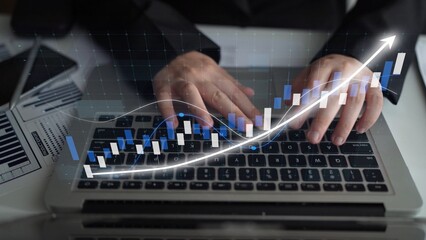 Hands on a laptop keyboard represent business analytics and financial growth, with a rising graph overlay illustrating success in stock market trends and data analysis. Copula