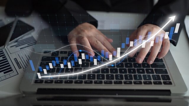 Hands on a laptop keyboard represent business analytics and financial growth, with a rising graph overlay illustrating success in stock market trends and data analysis. Copula