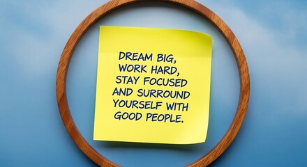 Motivational message dream big work hard on yellow sticky note with wooden circle