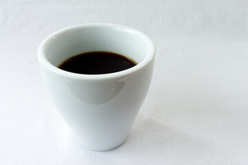 Steaming black coffee in a modern white ceramic cup on a bright high-key background. Morning routine, energy and caffeine boost concept with ample copy space for text.