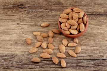 Close up of fresh almonds spilled out of wooden bowl