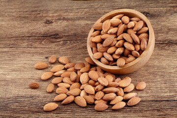 Close up of fresh almonds spilled out of wooden bowl