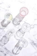 Five different glasses, with reflections and shadows on the marble surface, sunlight, no people,