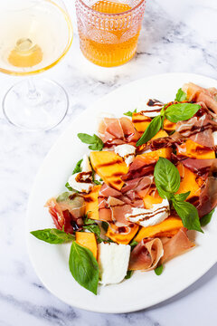 Salad with prosciutto and melon, with arugula and cheese, with a glass of wine, natural light,
