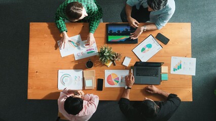 Top view of diverse businesspeople discuss about financial plan at meeting while looking at stock market statistic and explain marketing idea at meeting room. Creative startup concept. Convocation.
