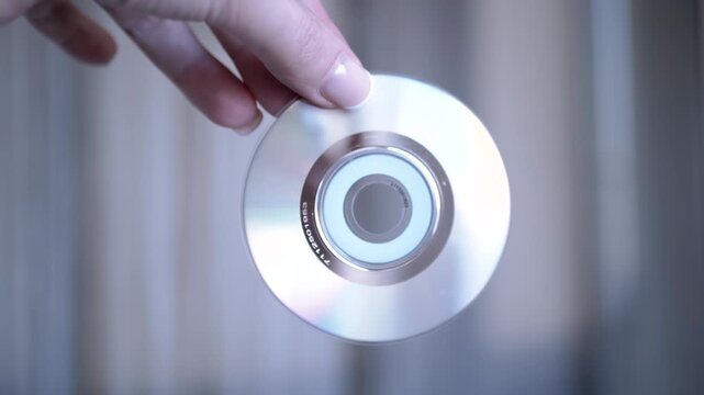 A hand holds a blank CD against a softly blurred background, creating a simple yet evocative image of data storage.
