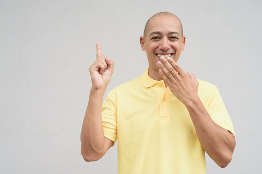 Portrait of bald Hispanic man laughing against plain white background wall - Powered by Adobe