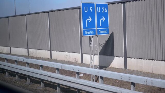 Highway signs indicating directions to Berlin and Chemnitz, with a noise barrier in the background. Useful for travel, navigation, and German road network videos.