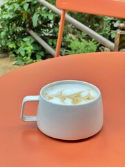 Latte cappuccino coffee in white cup on table in street cafe